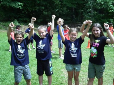 four campers holding hands in the air